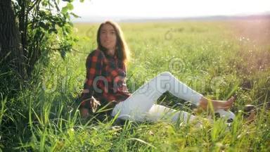 日落<strong>时</strong>分，年轻女子坐在一片绿色的田野里，<strong>靠近</strong>一个球。